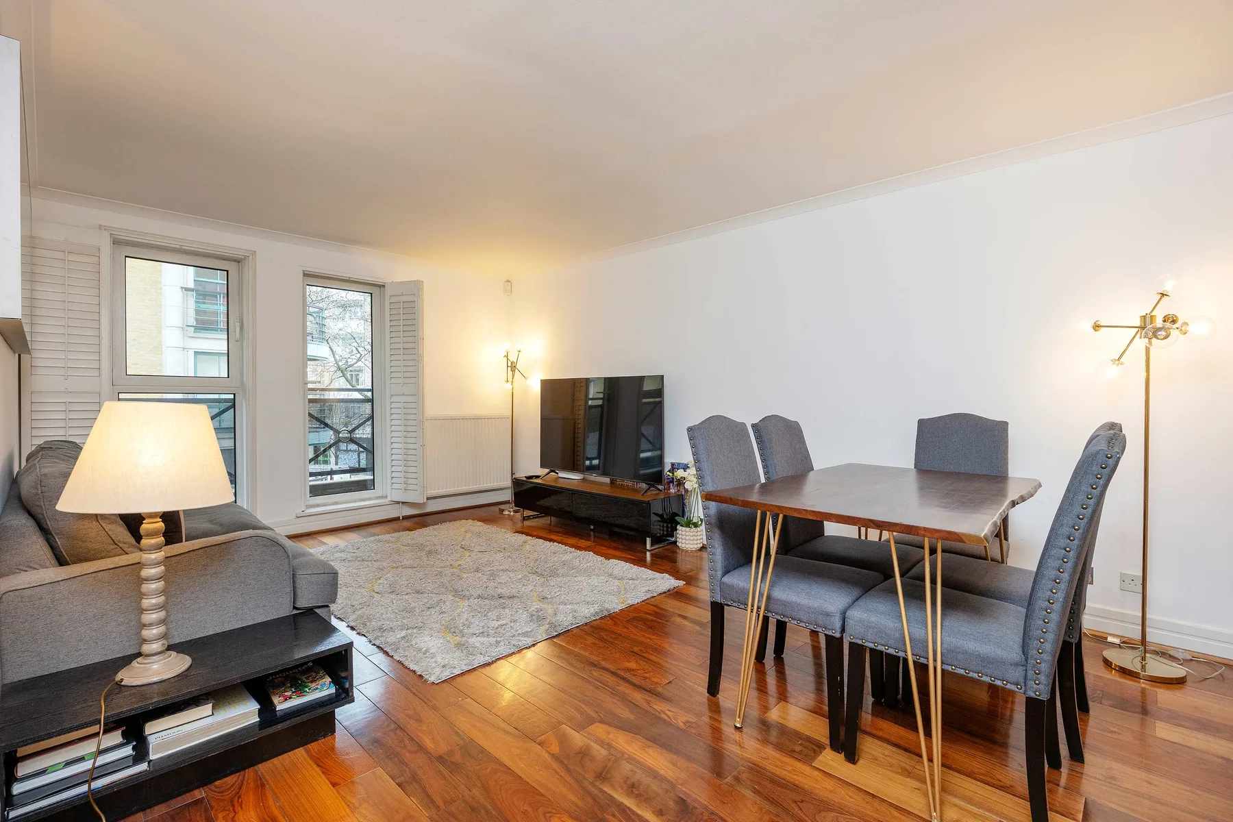 A combined living and dining area with a television, table, and seating.