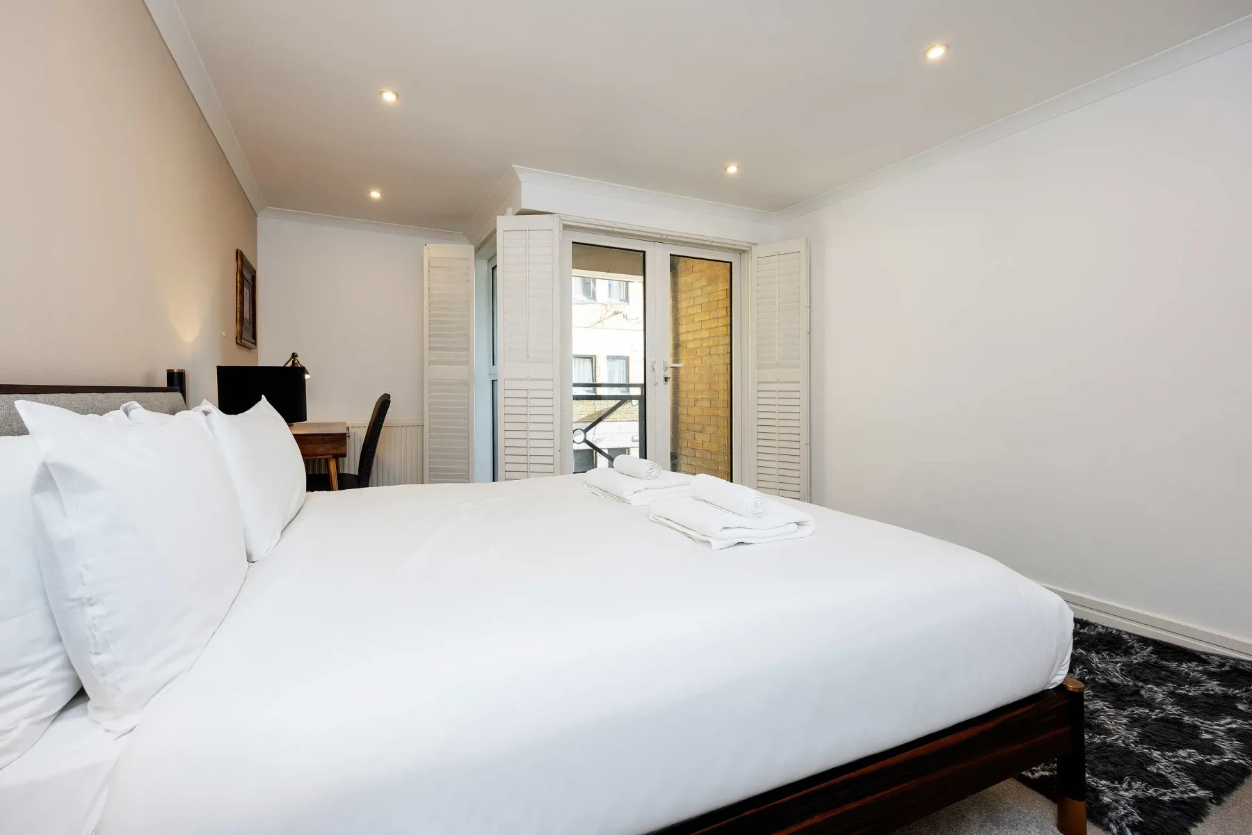 A bedroom with a large bed, white bedding, and a window.
