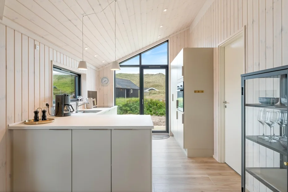 A bright kitchen with a large island and tall windows overlooking greenery.