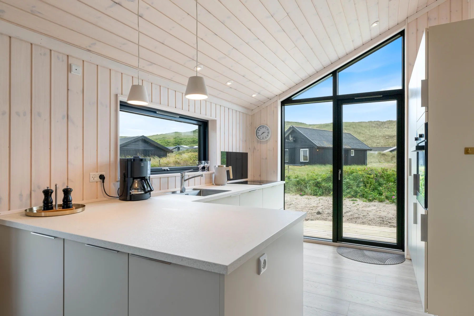 A bright kitchen with a central island and large windows overlooking the landscape.