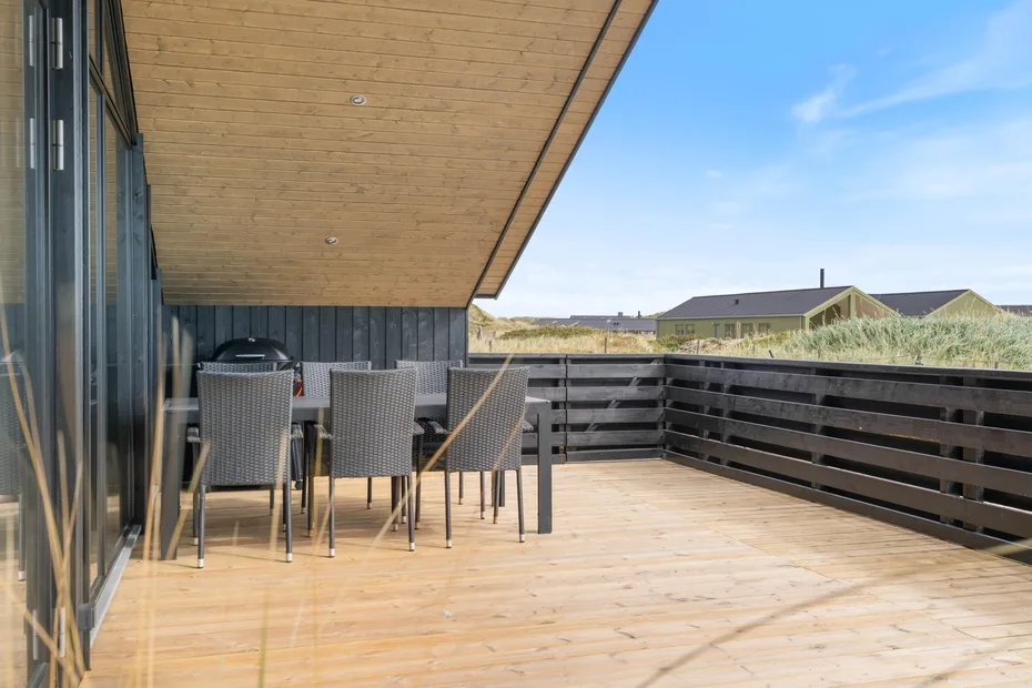 A spacious outdoor deck with dining seating beneath a covered roof.