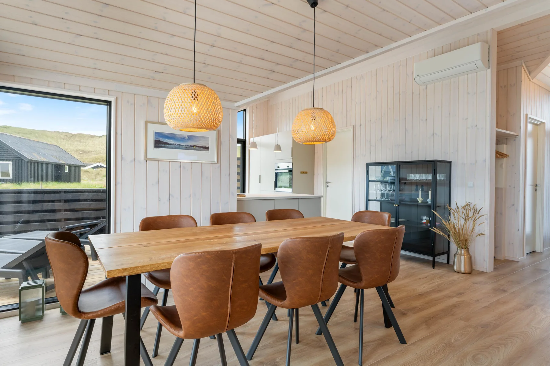 A dining area with a wooden table and brown seating beside a kitchen.