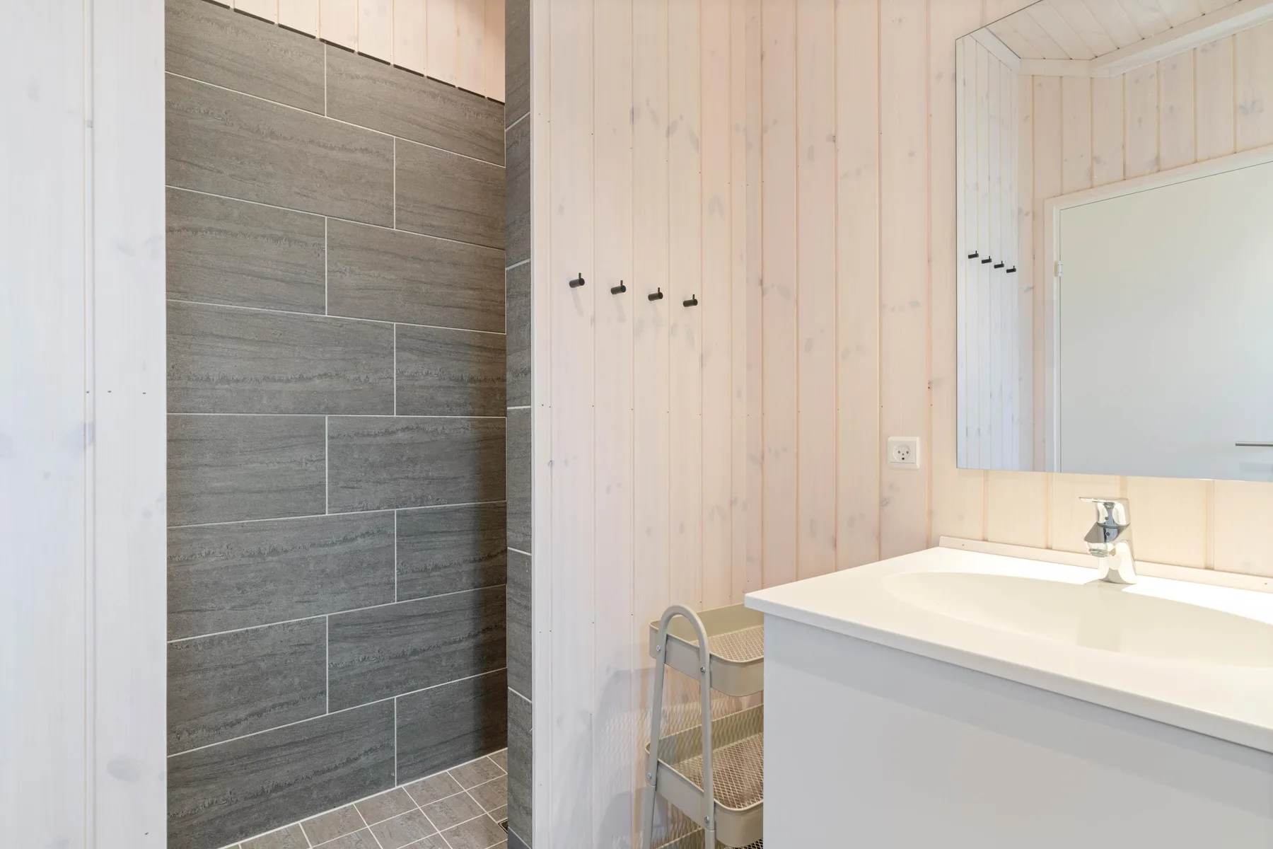 A bathroom with a tiled shower area and a sink beneath a mirror.