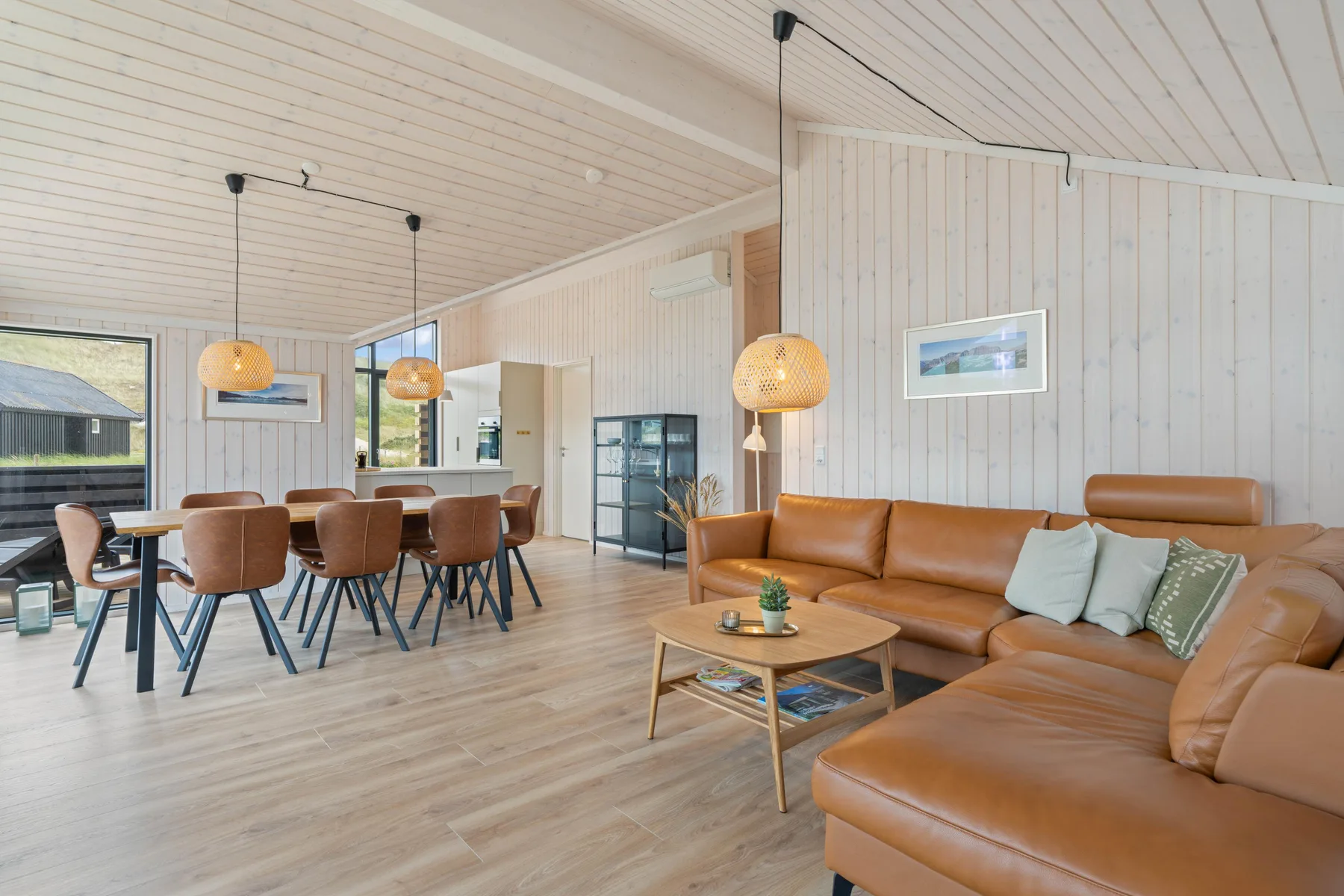 A bright living and dining area features leather seating and a dining table.