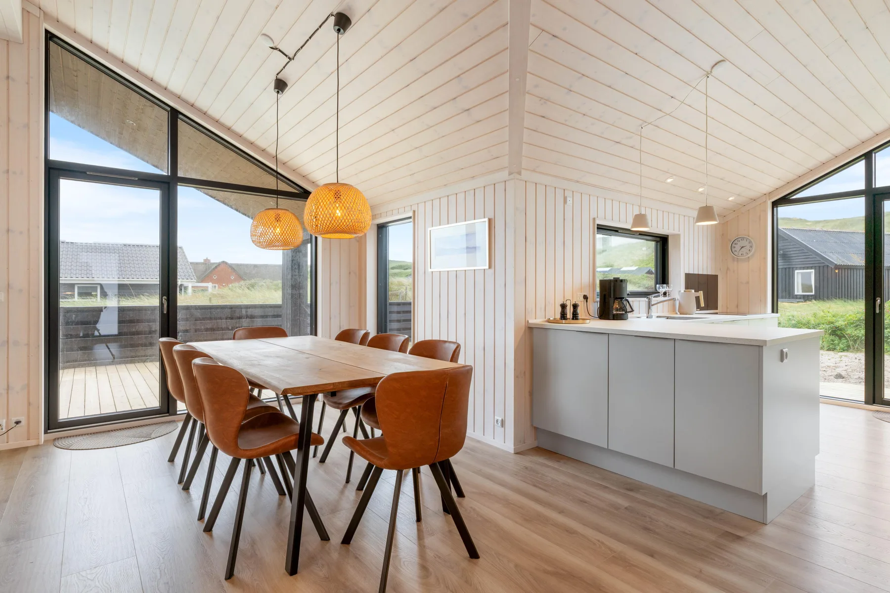A bright open-plan dining and kitchen area with large windows.