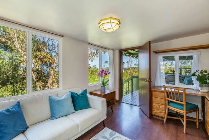 A bright living room with a sofa beside an open door to a balcony.