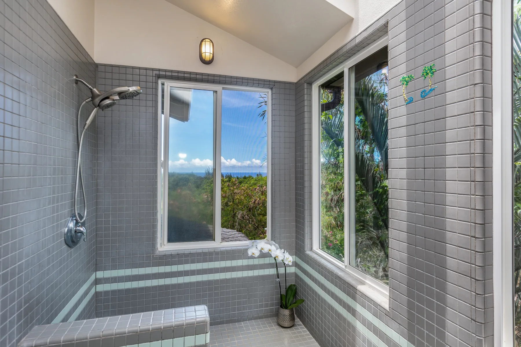 A tiled shower area with large windows overlooking greenery.