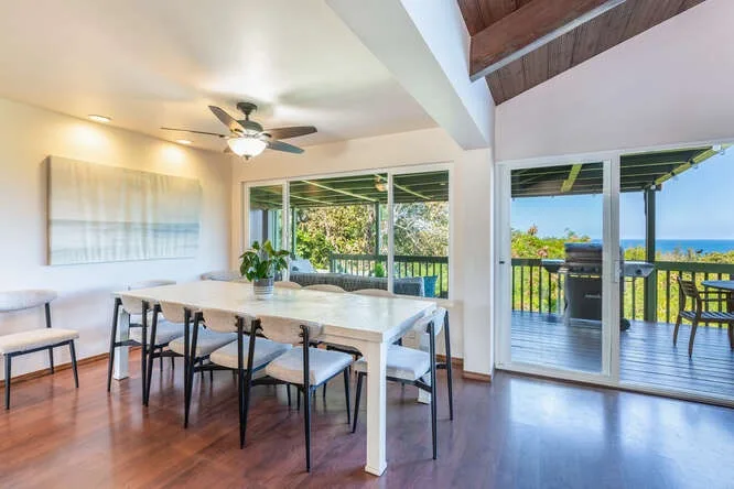 A dining area with a long table and sliding glass doors opening onto a deck.