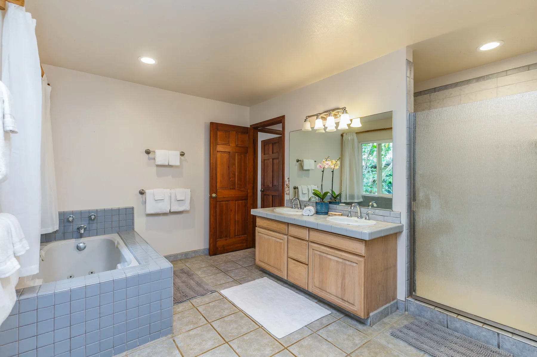 A bathroom with a tiled bathtub, vanity, and glass shower.