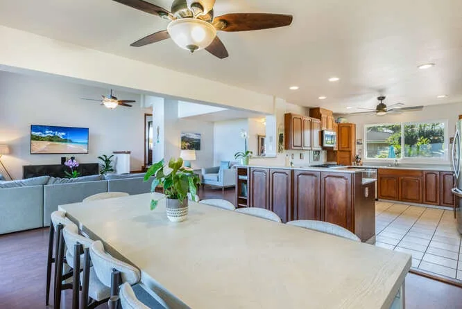 An open-plan living and dining area with a kitchen and ceiling fans.