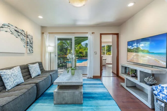 A bright living room with a sectional seating area, coffee table, and television.