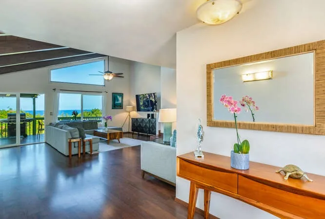 A bright living room opens onto a balcony, with seating beside large windows.