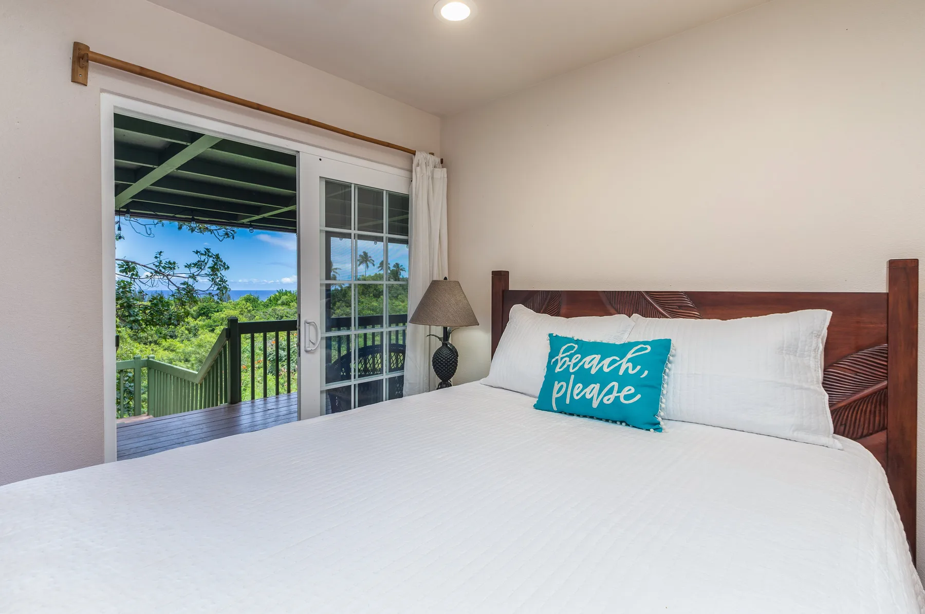 A bedroom with a large bed beside a sliding glass door overlooking a balcony.