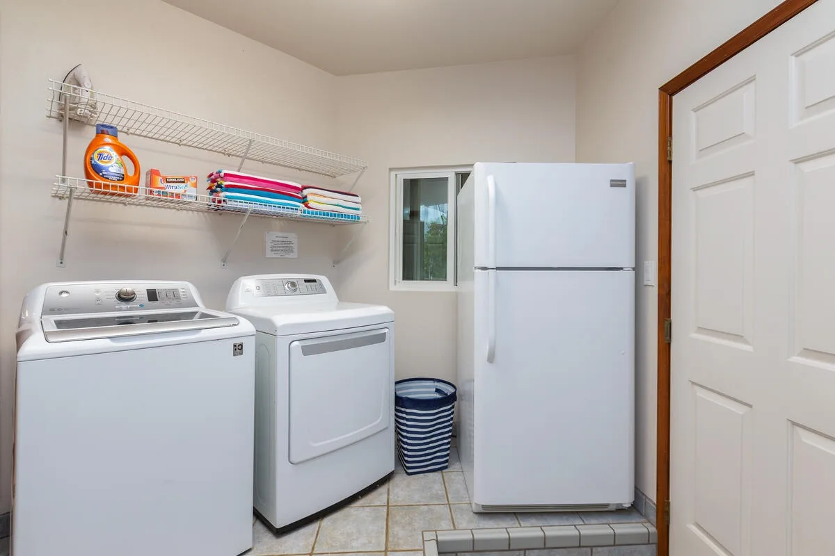 A laundry room with a washer, dryer, and refrigerator.