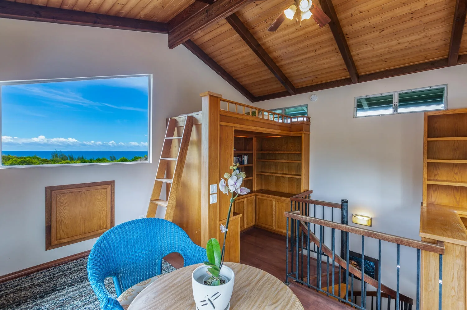 A loft sitting area with a blue woven chair, wooden shelving, and a sloped ceiling.