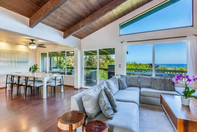A living and dining area opens onto large windows overlooking the water.