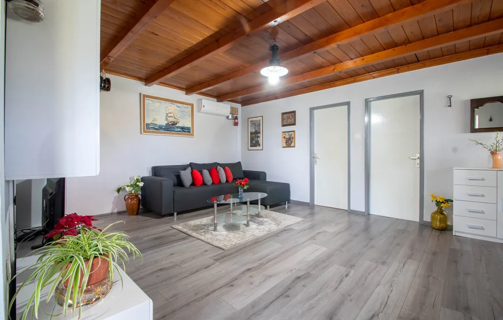 Una sala de estar con asientos oscuros, una mesa de centro de vidrio y un techo de madera.