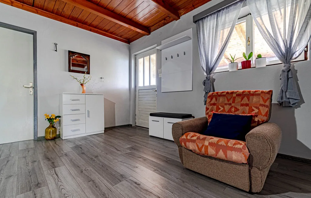 Una zona de estar con un sillón tapizado junto a una ventana con cortinas.