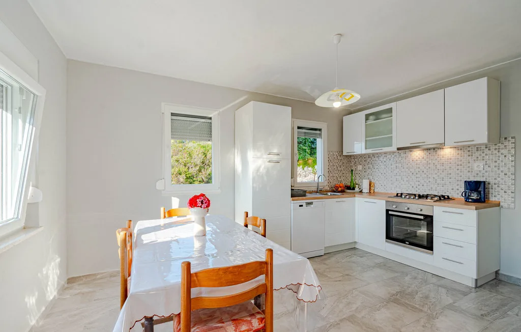 Una cocina y comedor luminosos con gabinetes blancos y una mesa.