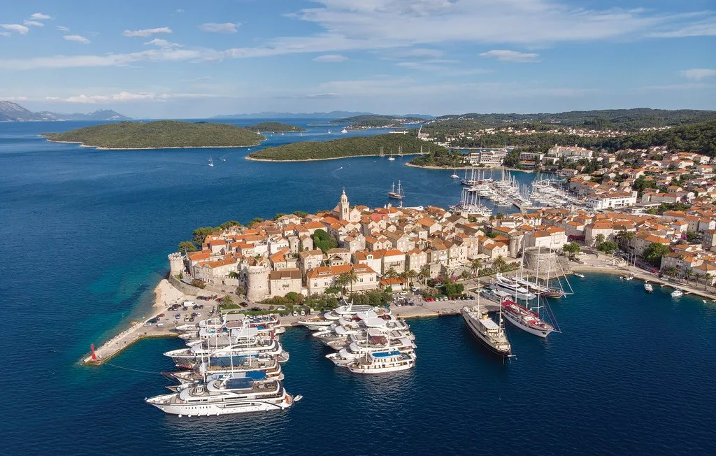 Vista aérea de un pueblo costero junto a un puerto lleno de barcos.