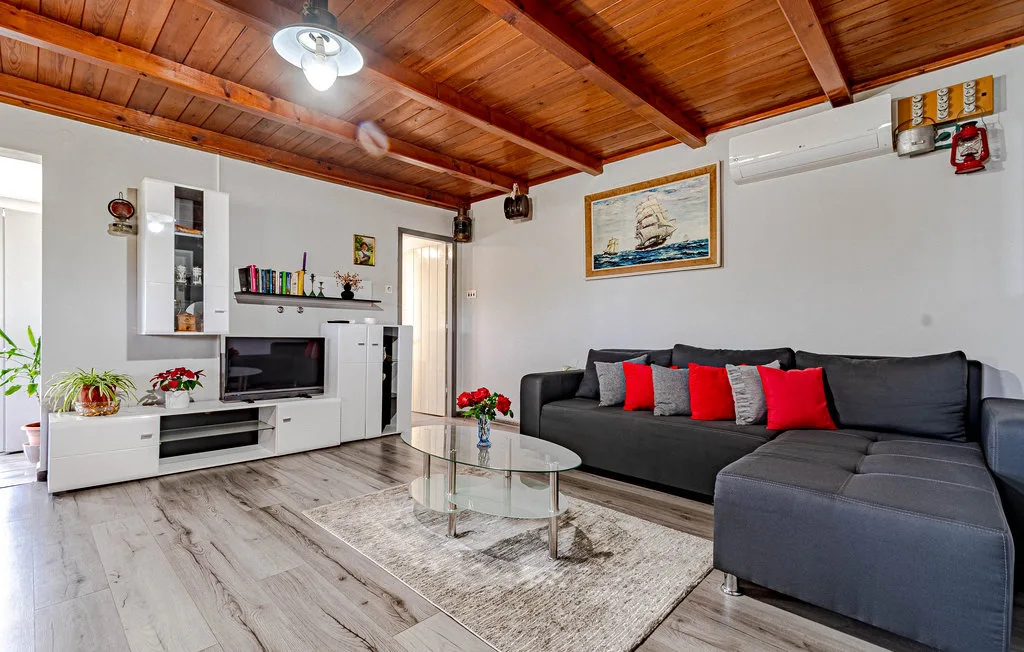 Una sala de estar con asientos oscuros y una mesa de centro de vidrio.