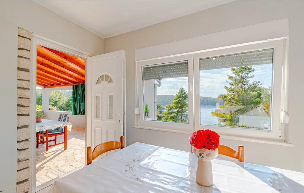 Comedor con una mesa junto a grandes ventanas con vistas al agua.