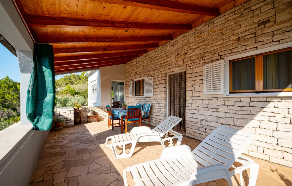 Un patio cubierto de piedra con asientos al aire libre junto a una casa revestida de piedra.