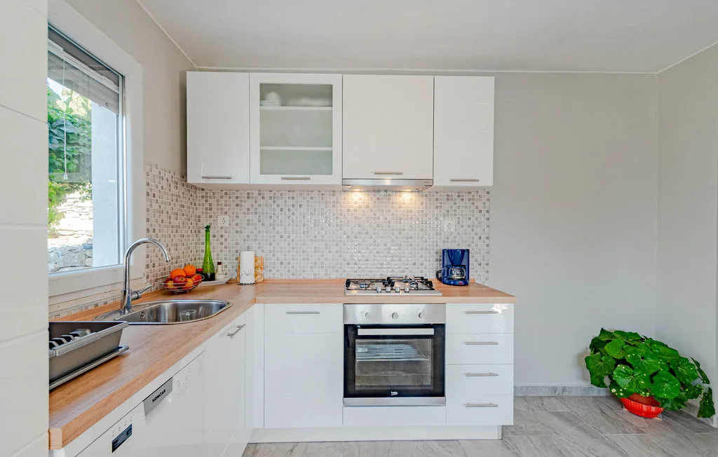 Una cocina luminosa con gabinetes blancos, una encimera y un horno empotrado.