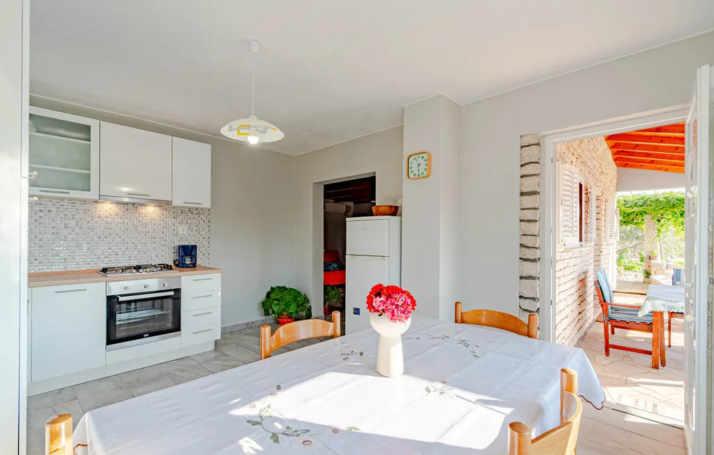 Un comedor luminoso con una mesa junto a una cocina compacta y una puerta abierta al patio.