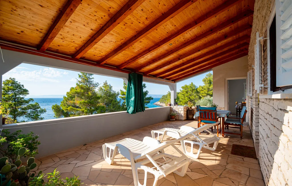 A covered terrace with seating and loungers overlooks the sea.