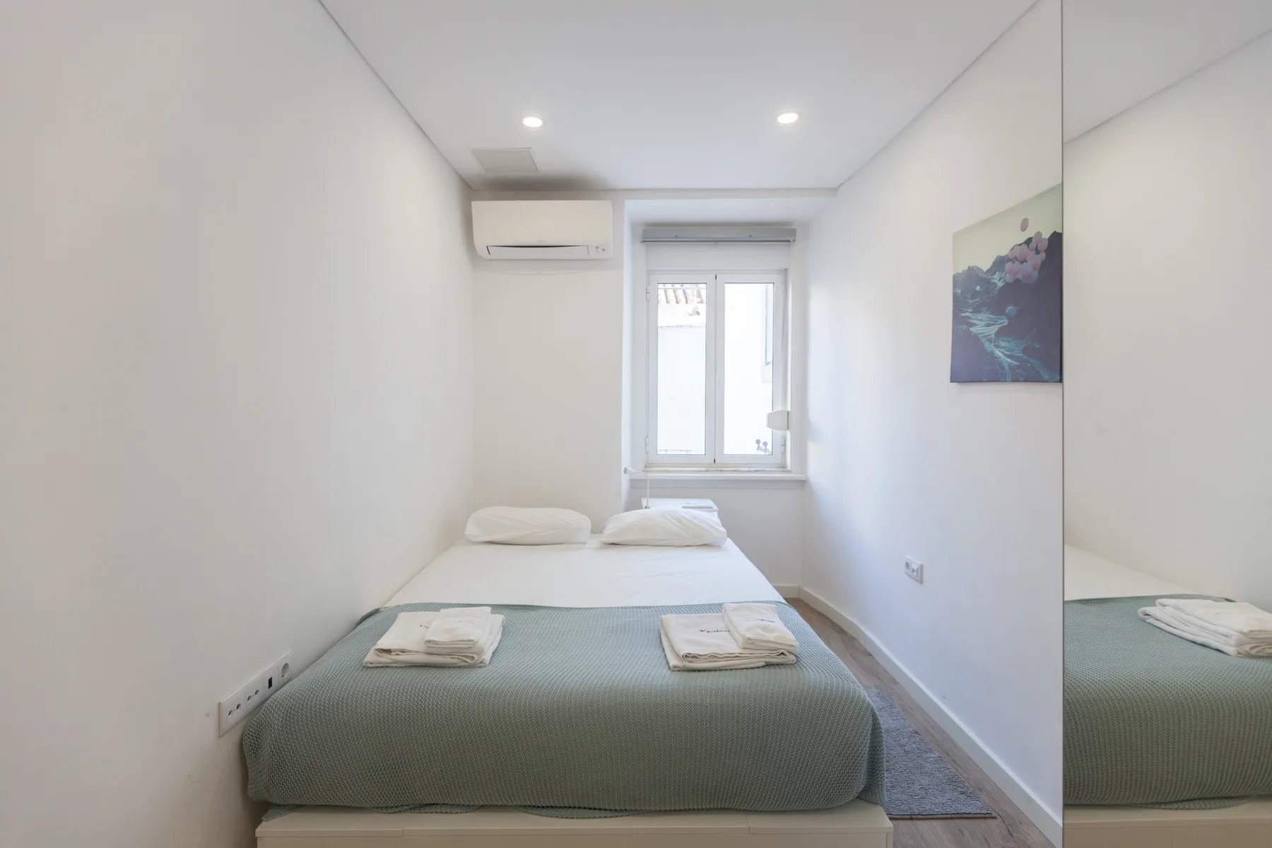 Un dormitorio compacto con una cama bien hecha bajo una ventana.