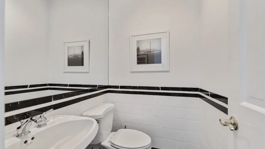 Un baño con bañera, inodoro y una franja negra horizontal en la pared.