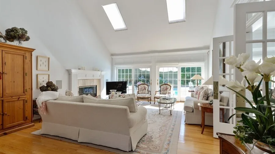 A bright living room with seating arranged around a coffee table and large windows.