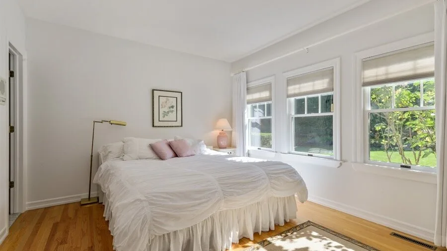 Un dormitorio luminoso con una cama junto a varias ventanas.