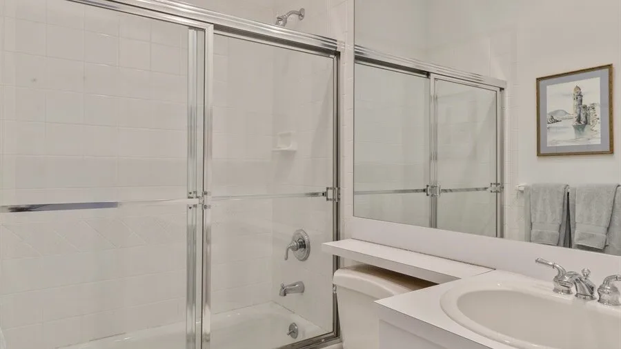 Un baño alicatado con una ducha de vidrio y un lavabo.