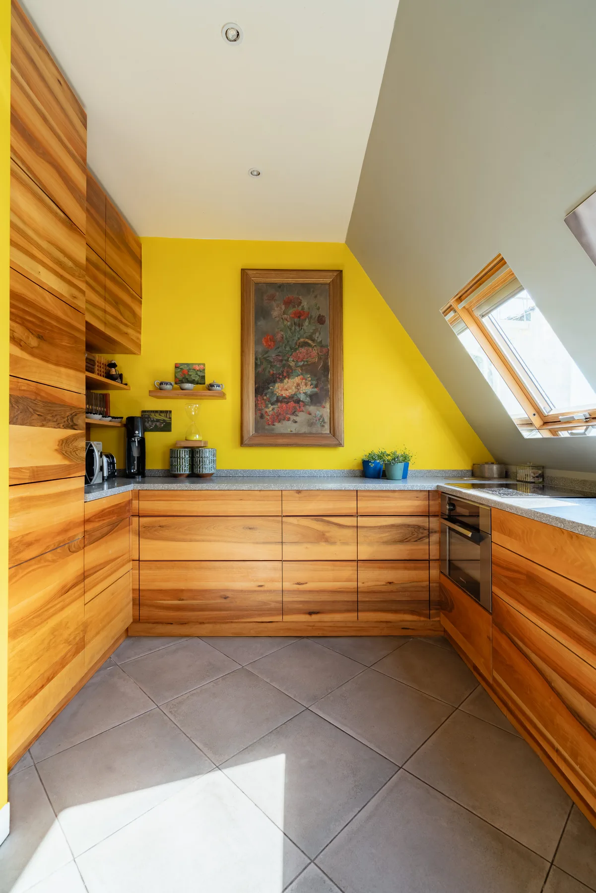 A kitchen with wood cabinetry, a yellow wall, and a slanted skylight.