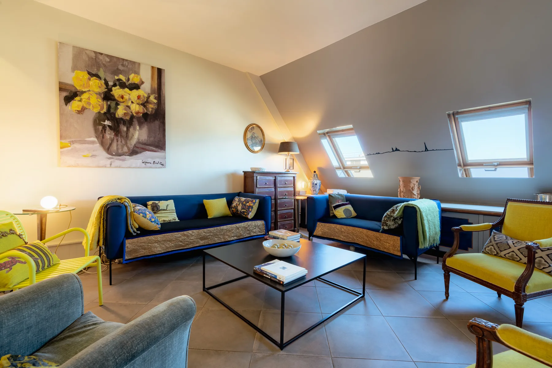 A living room with seating, a coffee table, and sloped ceilings.