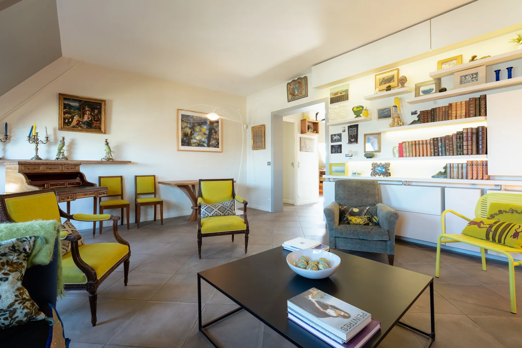 A living room with seating, a coffee table, and bookshelves along the wall.