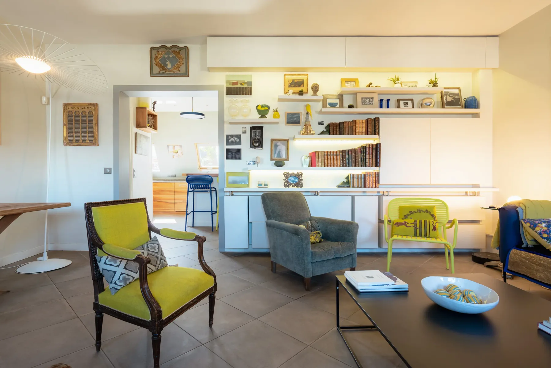 A bright living area with varied seating and built-in shelves along the wall.