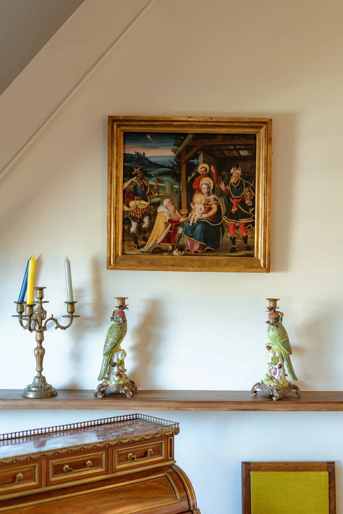 A framed painting hangs above a wooden console with decorative objects.