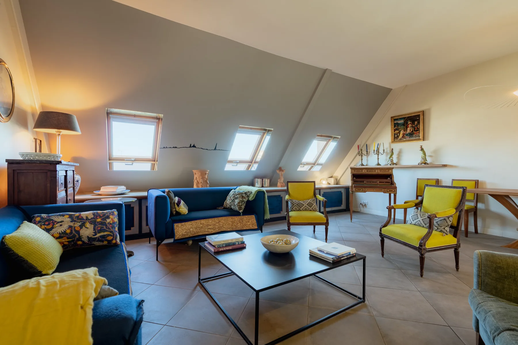 A furnished attic sitting room with seating arranged around a low coffee table.