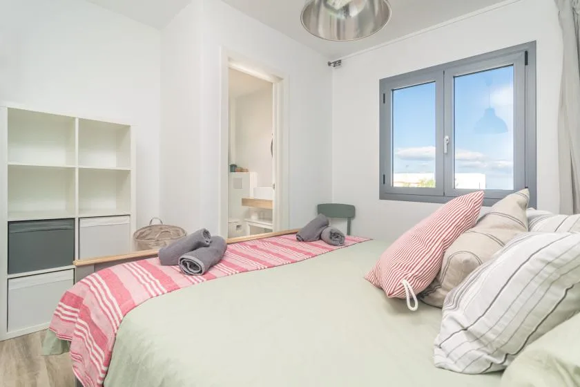 Un dormitorio luminoso con una cama vestida con ropa de rayas junto a una ventana.