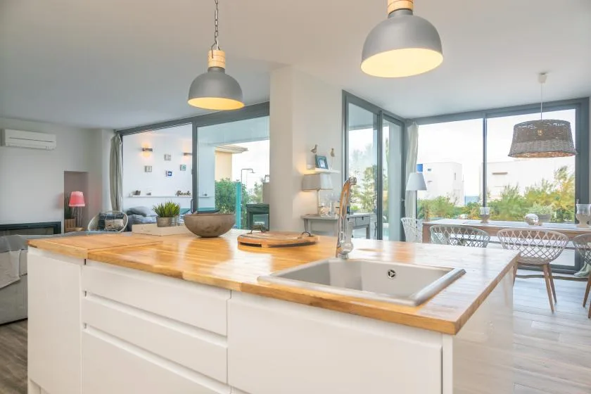 Una cocina luminosa con una isla grande y fregadero se abre a un comedor.