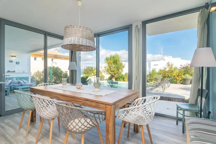 Comedor con una mesa de madera y vistas a través de grandes puertas de vidrio.
