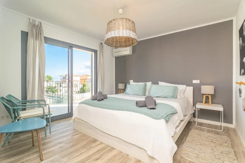 Un dormitorio luminoso con una cama grande y puertas de vidrio que dan a un balcón.