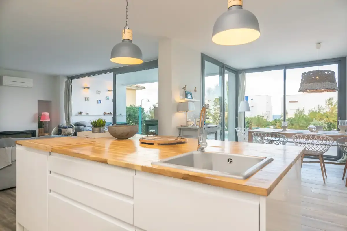 Una cocina luminosa y abierta con encimera de madera y zona de comedor.