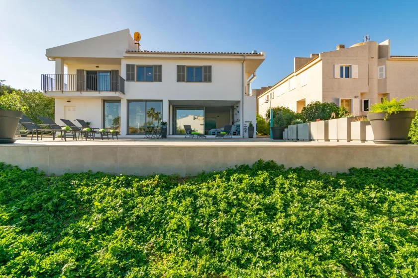 Una casa moderna da a una terraza con asientos al aire libre y vegetación.