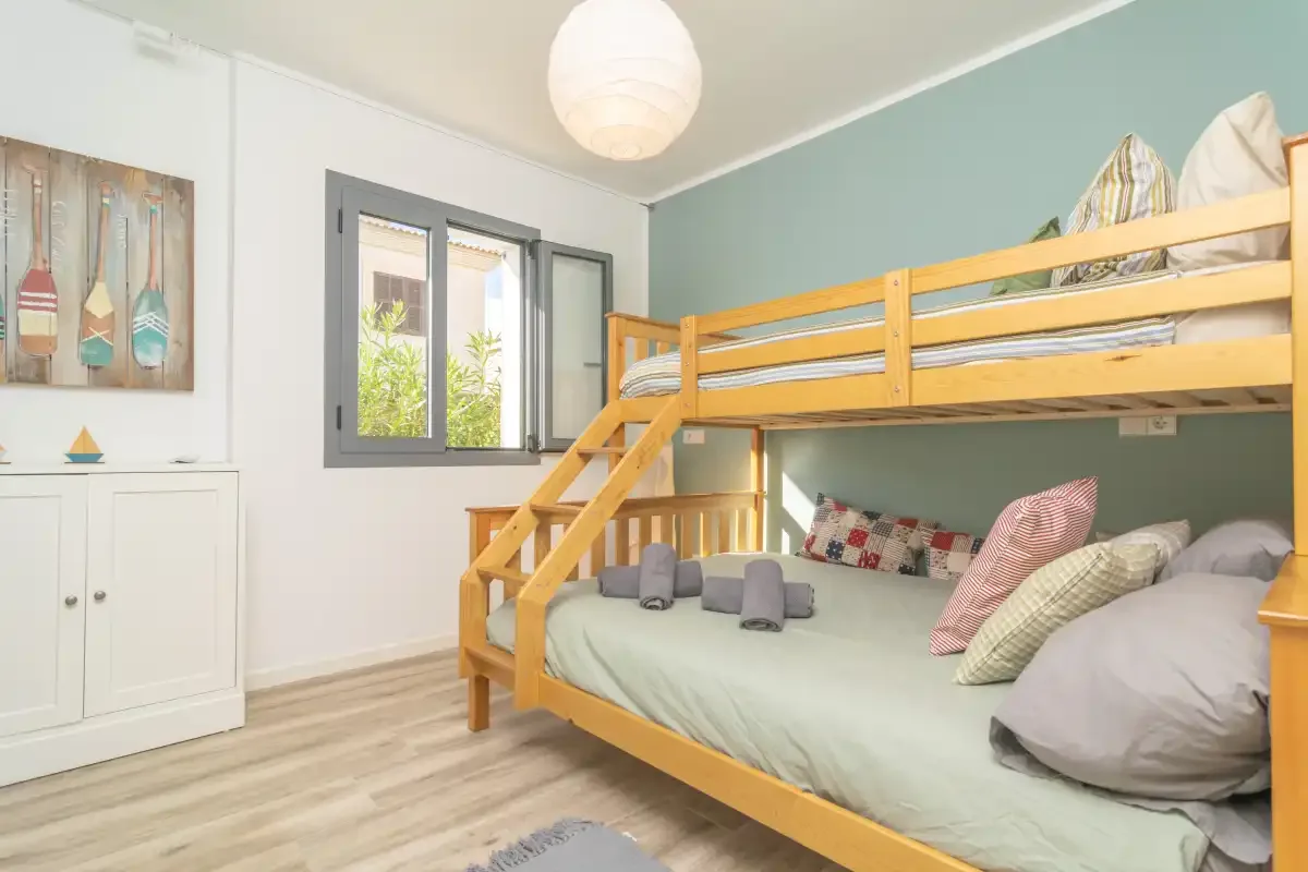 Un dormitorio cuenta con literas de madera, almohadas y ropa de cama.