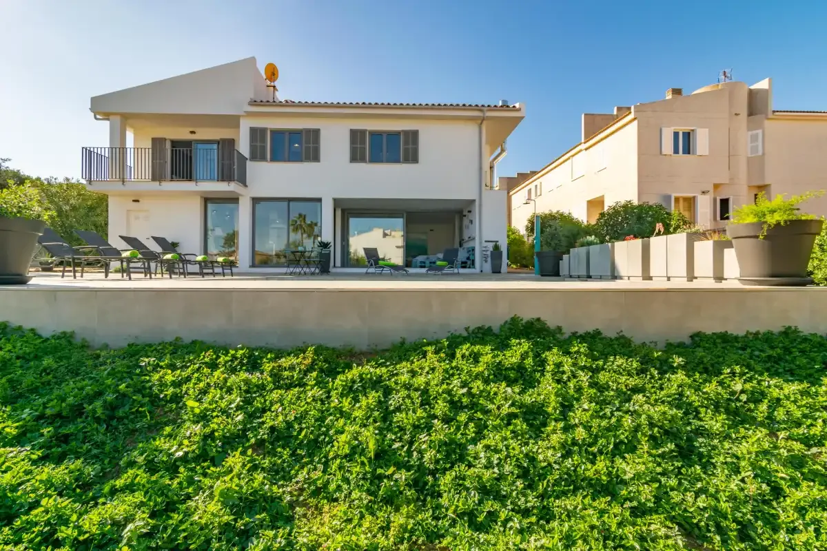 Casa moderna con una terraza que da a un jardín verde.