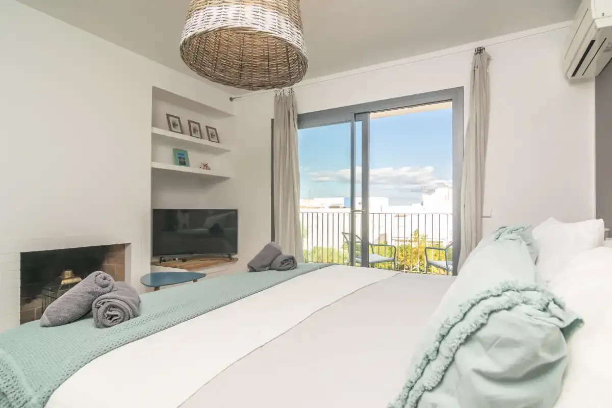 Un dormitorio con una cama, un televisor y puertas corredizas de vidrio que dan a un balcón.